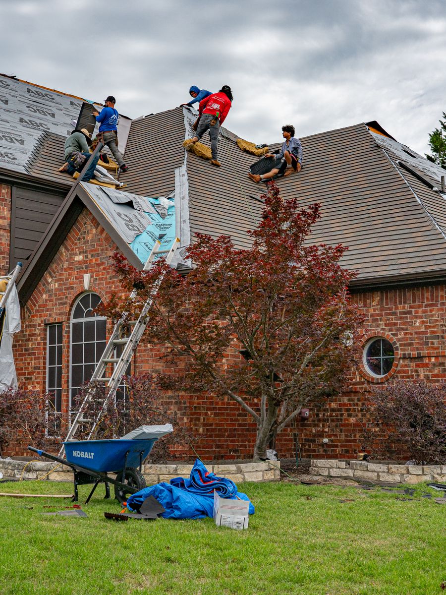 A roofing crew working on a house after storm damage